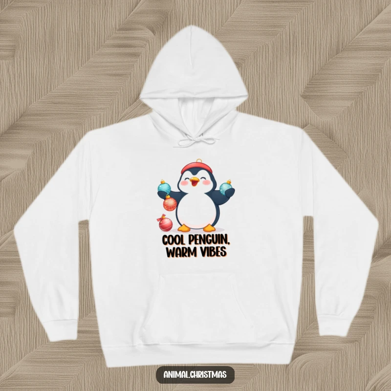 Funny Christmas hoodie showing a plump, beaming penguin trying to juggle three shiny Christmas baubles with great enthusiasm.