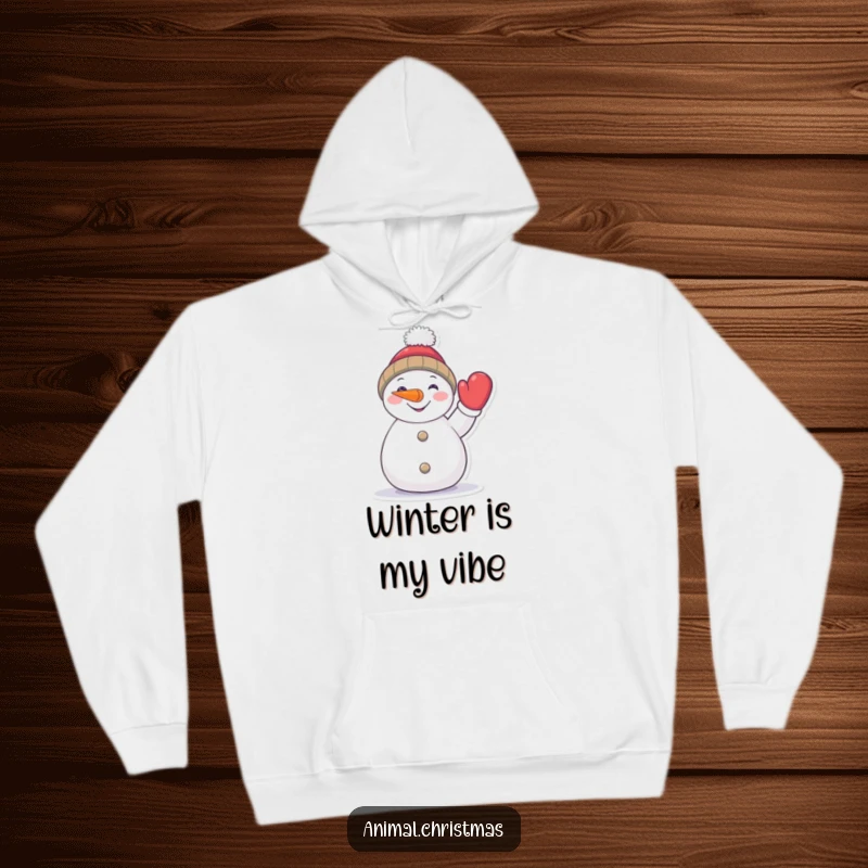 Funny snowman hoodie, a cheerful character with a carrot nose enthusiastically waving a mitten, warm winter clothing.