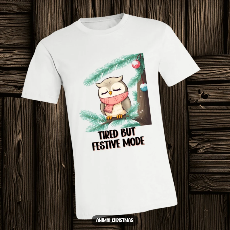 Funny Christmas t-shirt featuring a sleepy owl adorned with a knitted scarf, dozing peacefully inside a frosted pine tree.